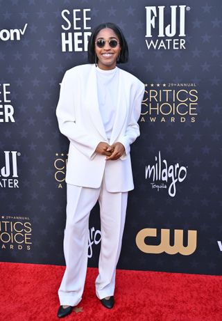 Ayo Edebiri wearing a white suit with sunglasses at the Critics Choice Awards.