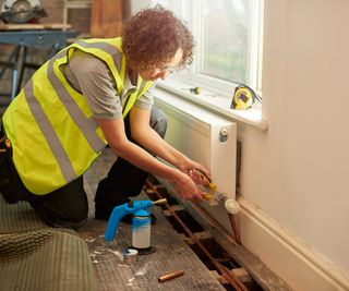 A female plumber installing a new radiator