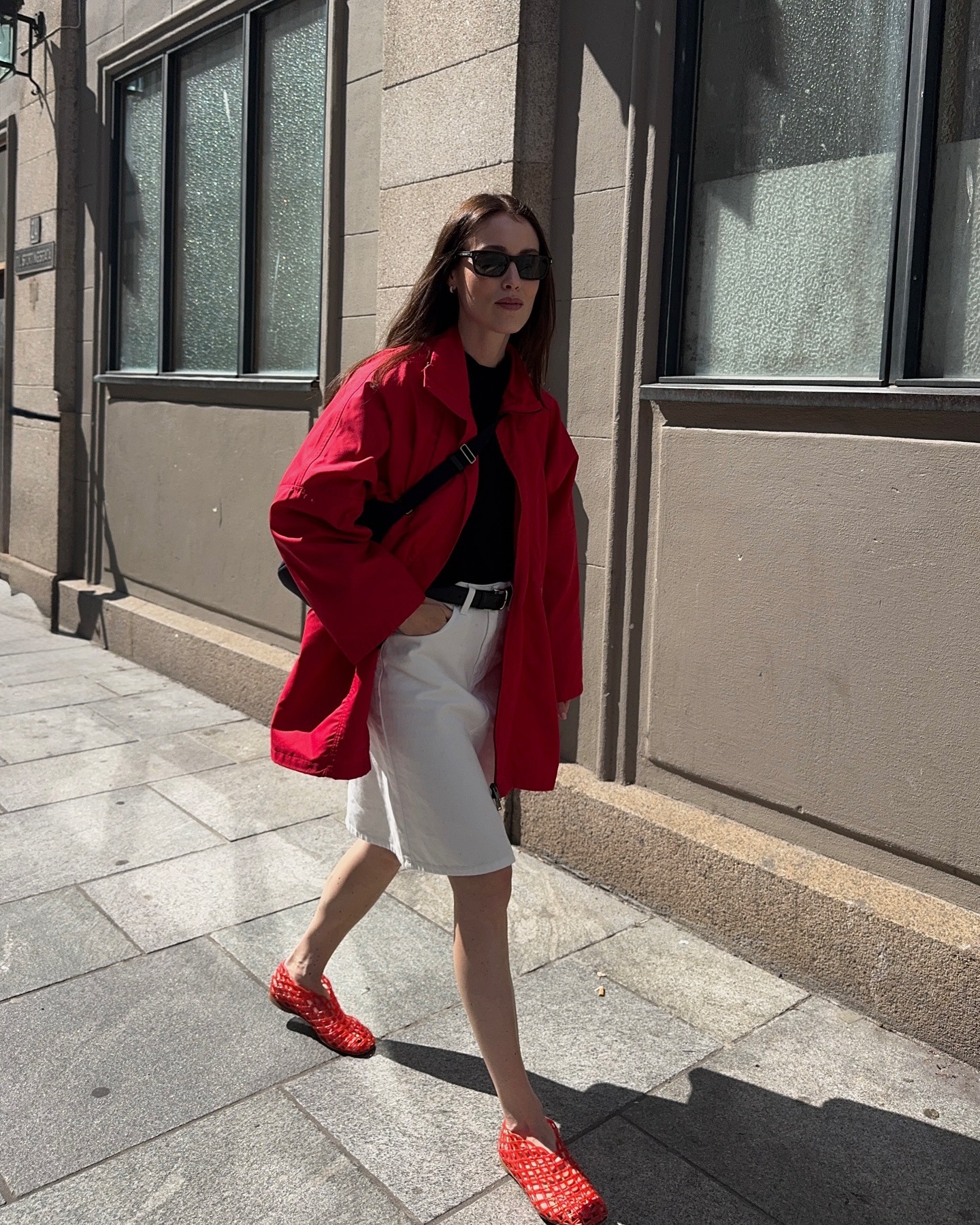 Annabel wears a red jacket, white Bermuda shorts, and red jelly flats.