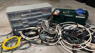 A collection of various cables that need to be sorted on a garage floor.