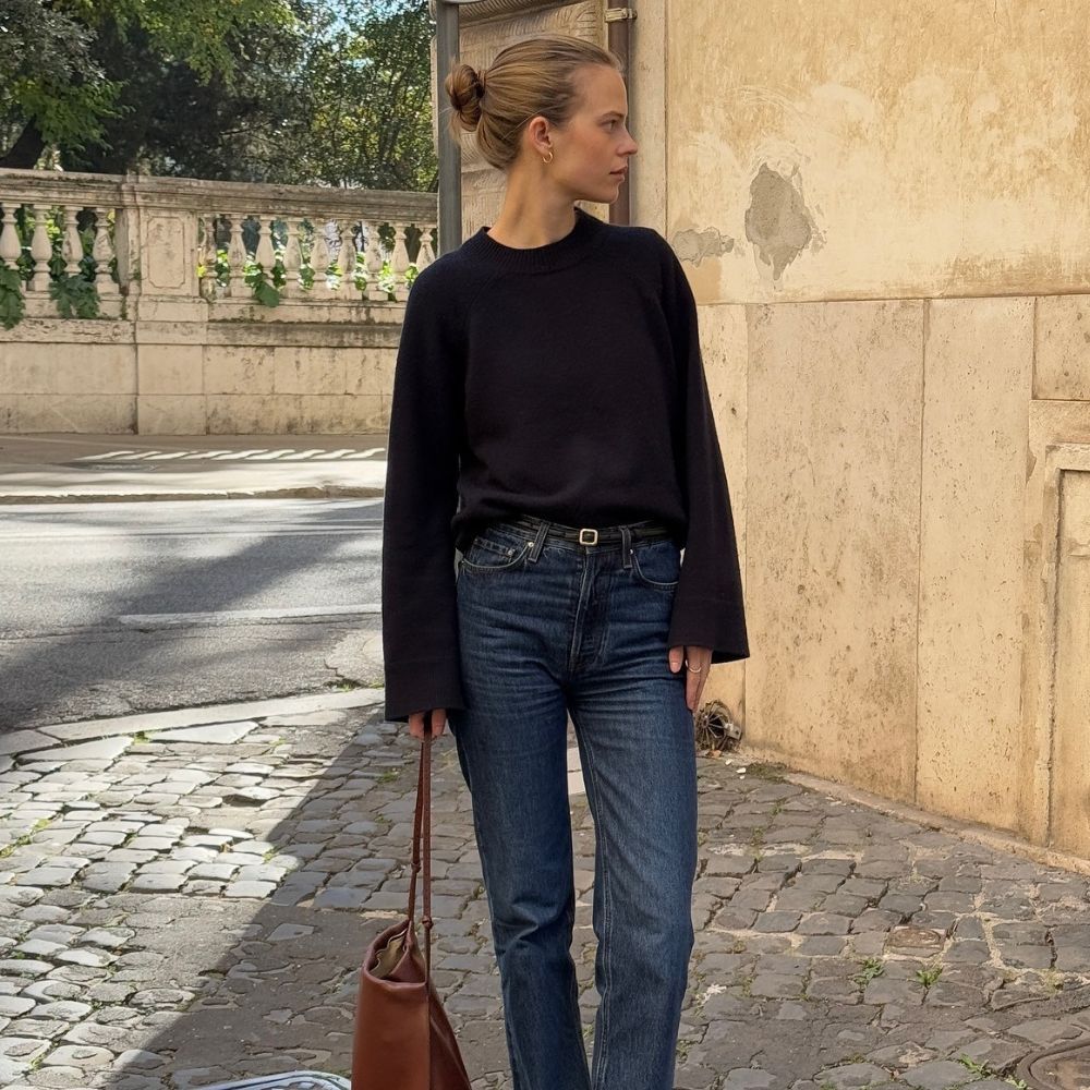 Influencer @claradyrhauge wears cigarette jeans with black pointed-toe boots and a black jumper.