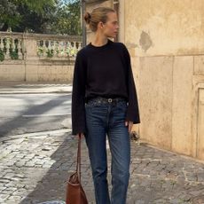Influencer @claradyrhauge wears cigarette jeans with black pointed-toe boots and a black jumper.