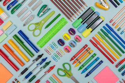 An image of various stationery on a blue background including marker pens, pencils, pencil sharpeners and rubbers. 