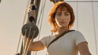 Emily Rudd holding one of the guide ropes on a ship as Nami in One Piece