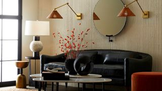 living room with black sofa, wall lights and circular mirror