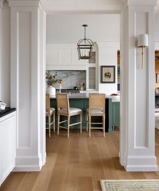 View through an archway to a white kitchen with green island