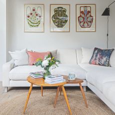 White painted living room with a white sofa and round jute rug underneath a wooden table