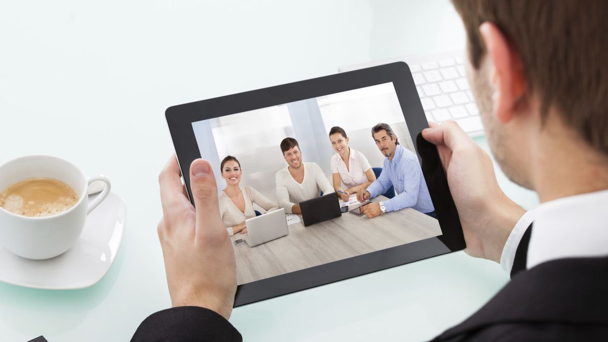 male teacher conferences with other teachers via tablet computer