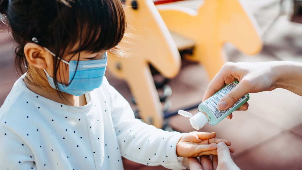 A child has her hands sanitised