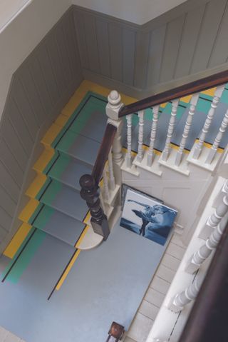A white staircase banister with painted treads and risers in blue, green and yellow design