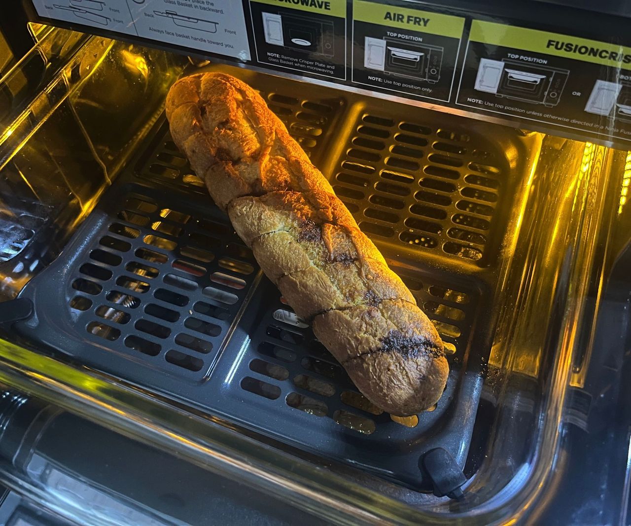 An overcooked garlic baguette in a pulled out glass air fryer dish