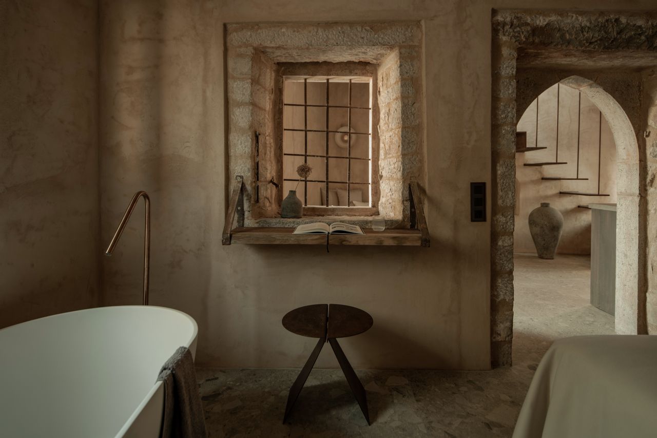A bedroom with limewash walls, and a large porcelain bathtub in the corner
