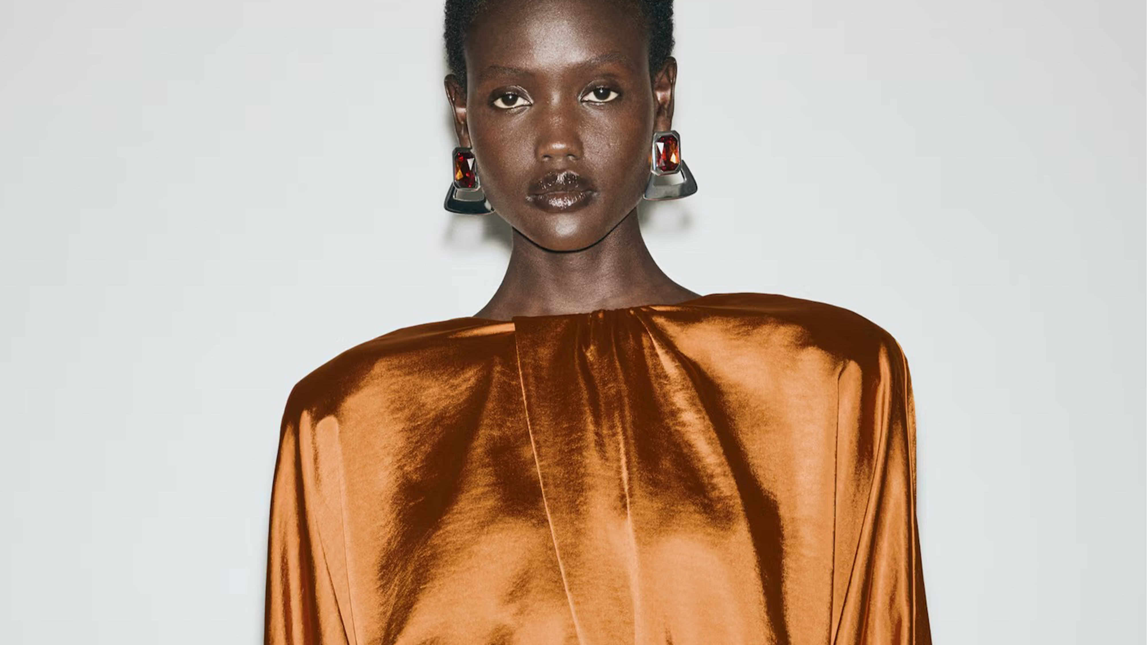 Photo of model wearing orange satin long sleeve dress.