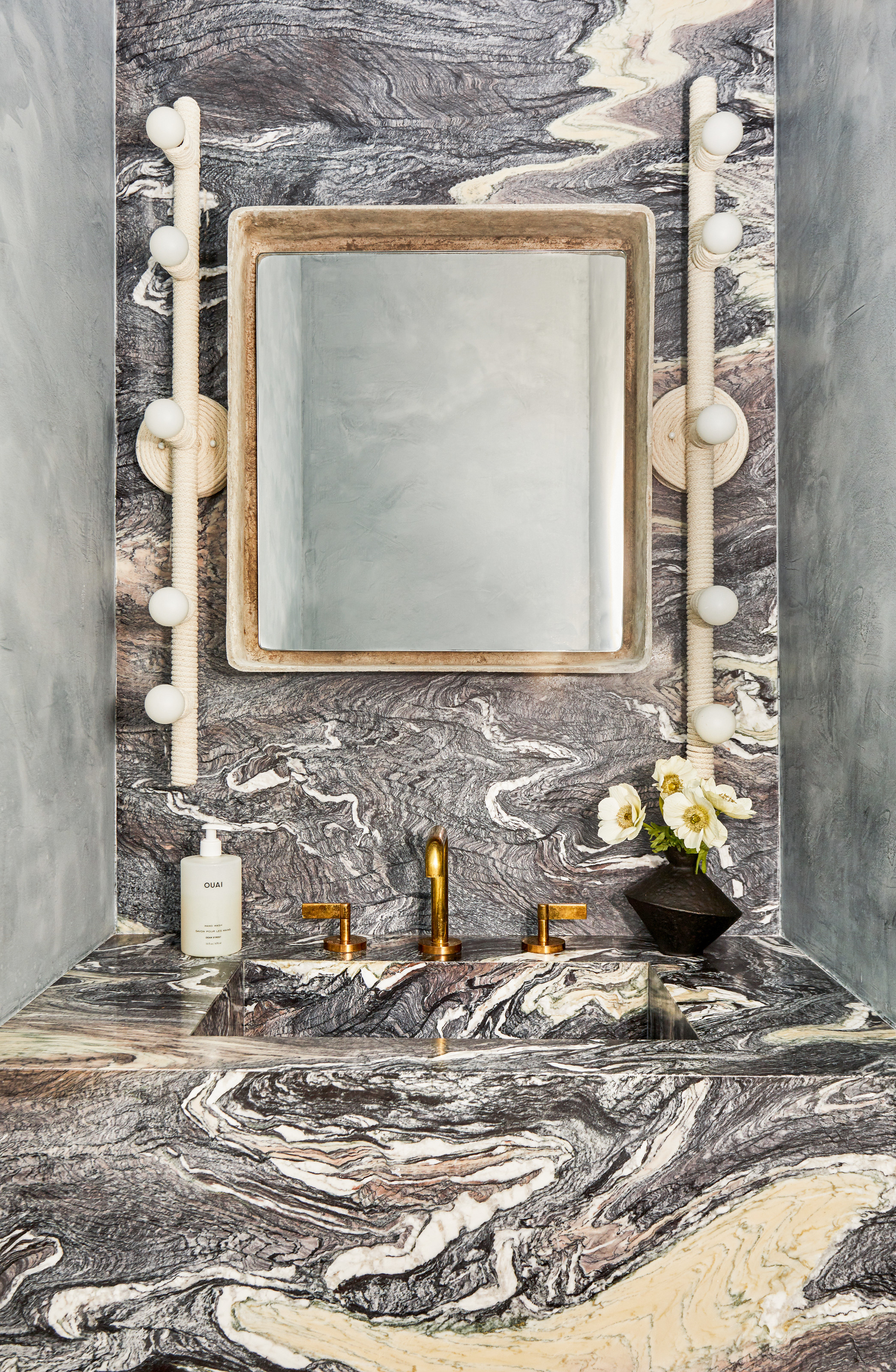 Close-up of a vanity area with dark blue-brown veined marble and studded wall lights