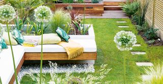 Landscaped garden with lawn and built in seating reas with bedding border to show a number of budget garden ideas