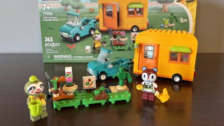 Lego Leif's Caravan & Garden Shop set, minifigures, vehicles, and box on a wooden surface