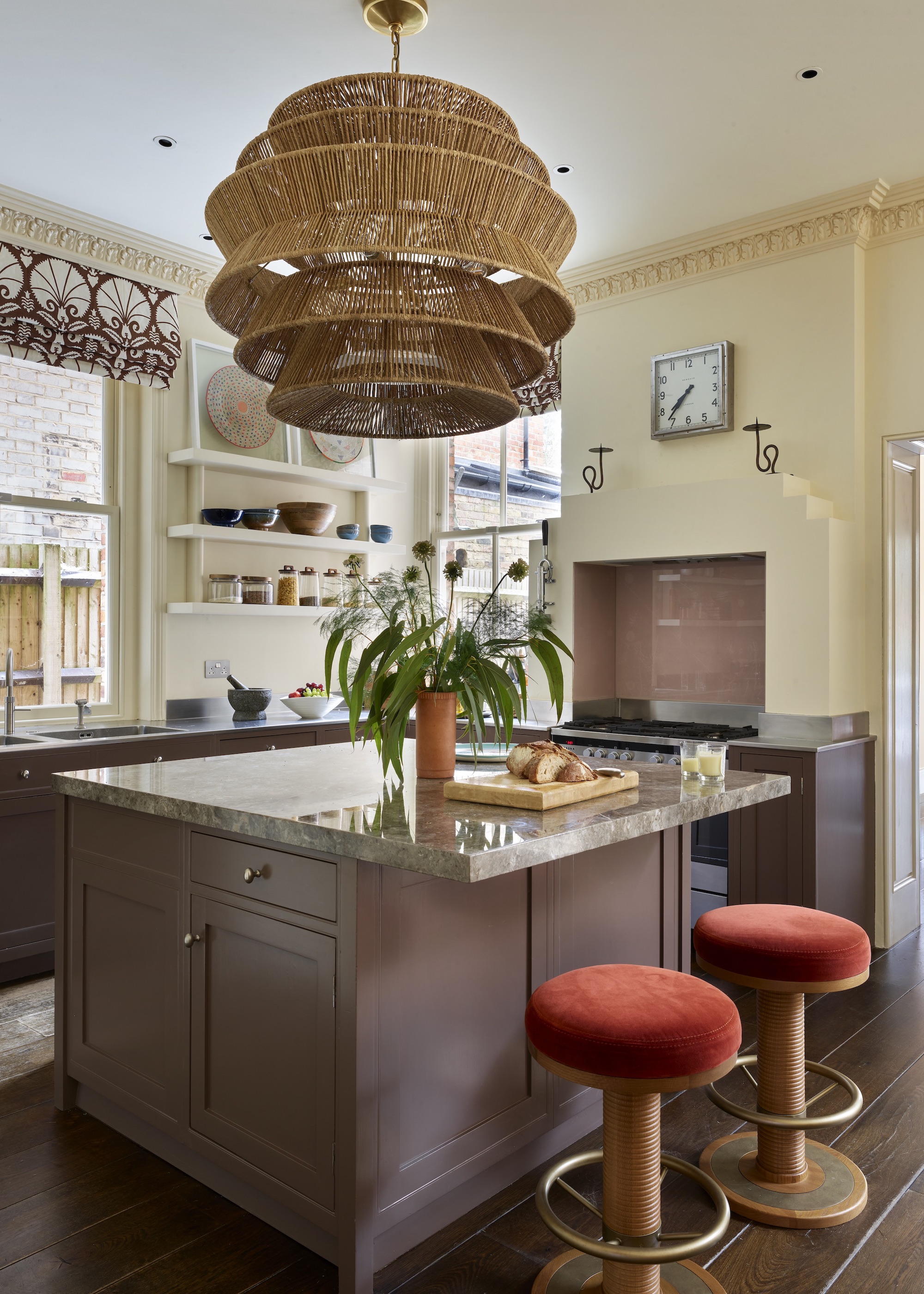 brown kitchen with large rattan chandelier and velvet stools