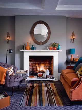 living room with gray wall fireplace with fire and candlelight wall sconces