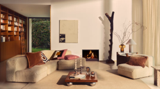 a living room with low profile furniture, a wooden coffee table, a fire place, lots of pillows, and a bookshelf against the left wall