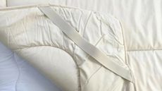 The corner of the Woolroom Mattress Topper, turned over so that you can see the elastic strap