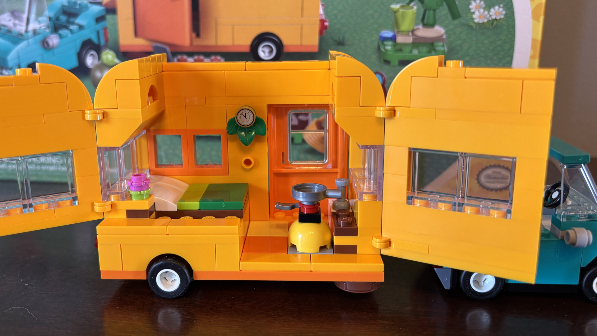 A side-on view of Lego Leif&#039;s Caravan, which is open and stood on a wooden surface