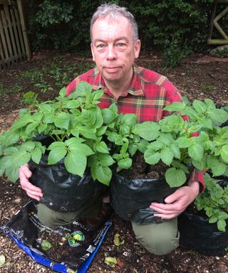 Garry Coward-Williams holding pots containing peat compost and peat-free compost