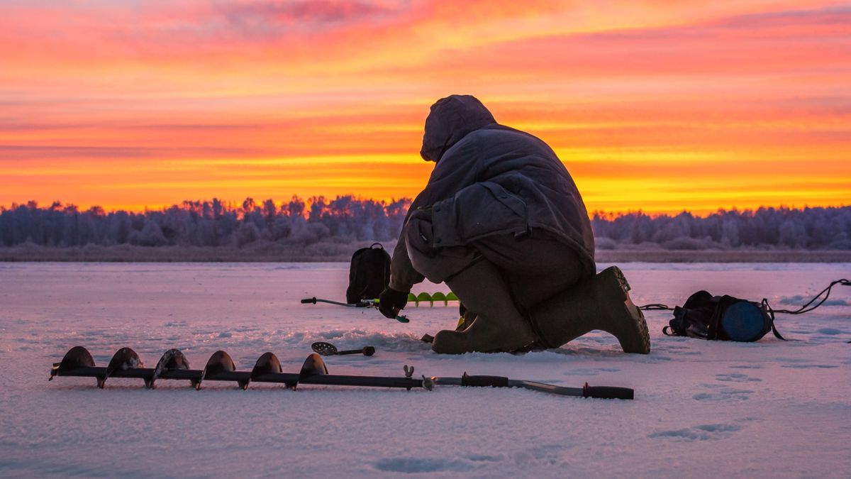 Man ice fishing at sunrise