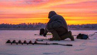 Man ice fishing at sunrise