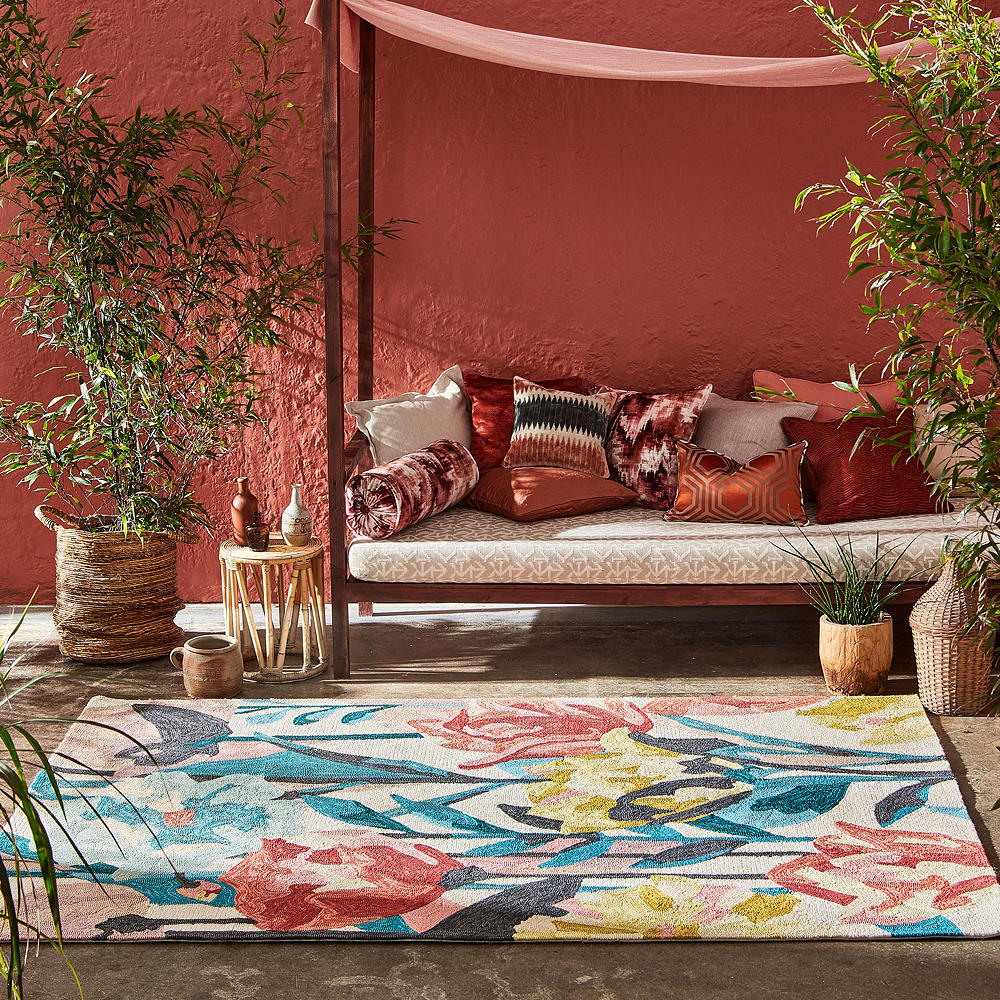 garden area with vibrant rug and red exterior wall with plant on pot