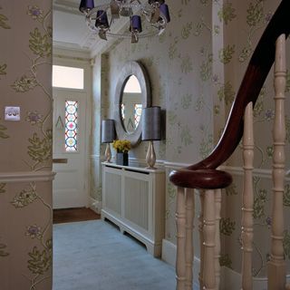 hallway with stair case and wallpaper wall