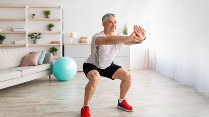 A man performing a squat at home as part of a joint strengthening routine 