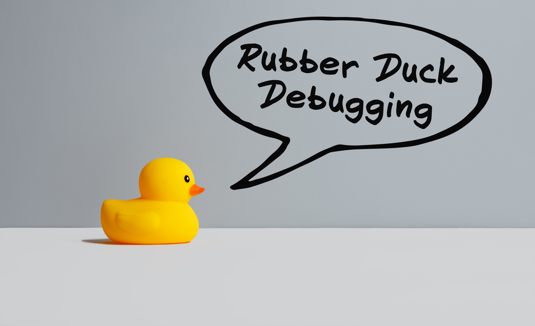 a rubber duck on a gray background with a speech bubble that reads &quot;rubber duck debugging&quot;