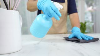 woman demonstrating how to clean marble with a mircrofibre cloth and spray