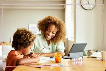 A mother helping her son with homework while sat at a table