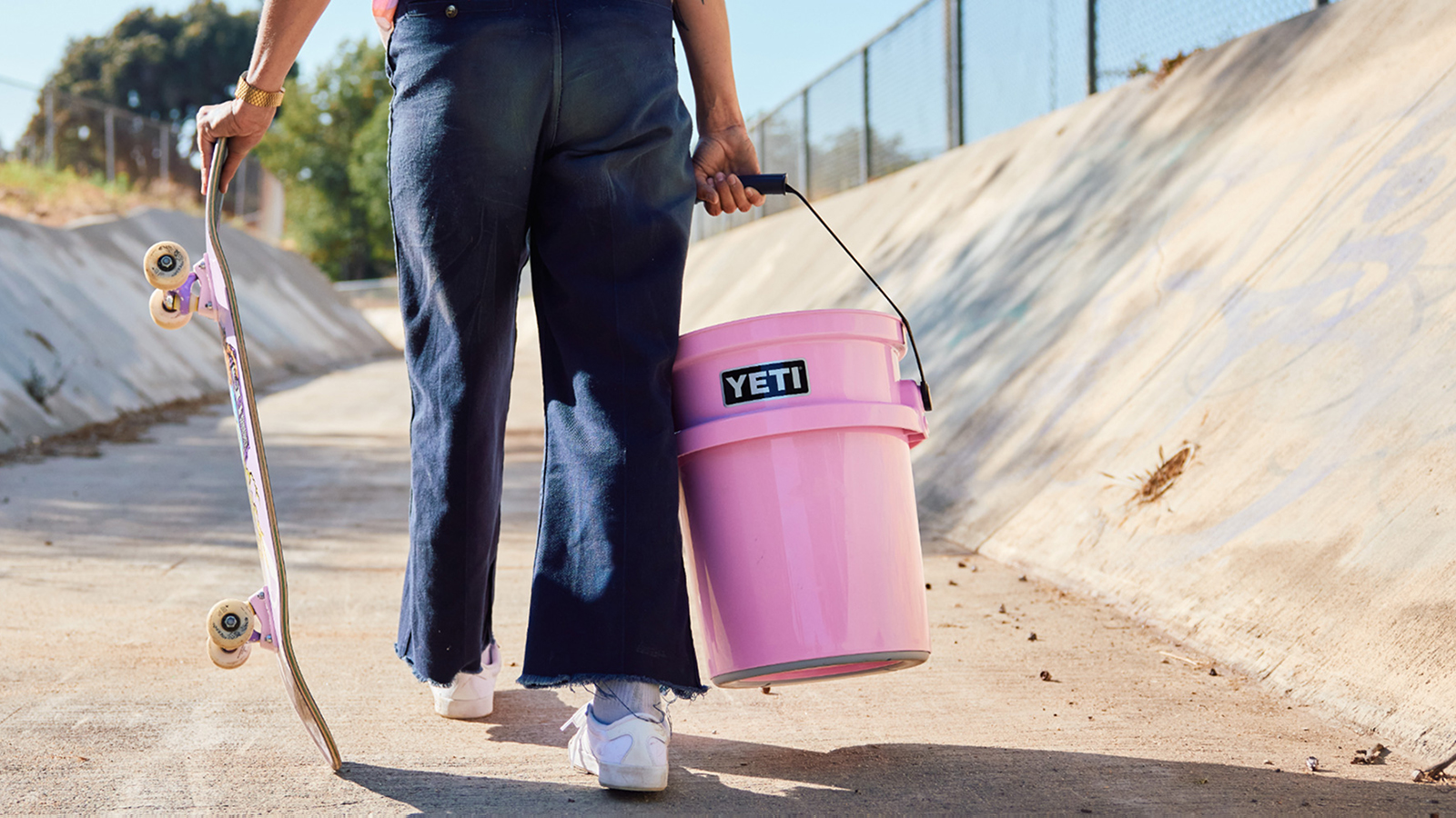 Person carrying a pink YETI bucket and a skateboard
