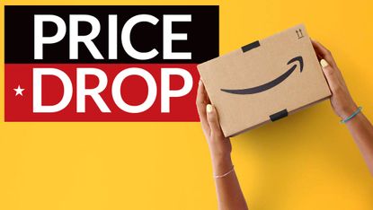 A hand holding an Amazon cardboard box with a price-drop badge