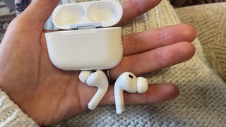 Apple AirPods Pro 3 held in a hand, with beige woollen background