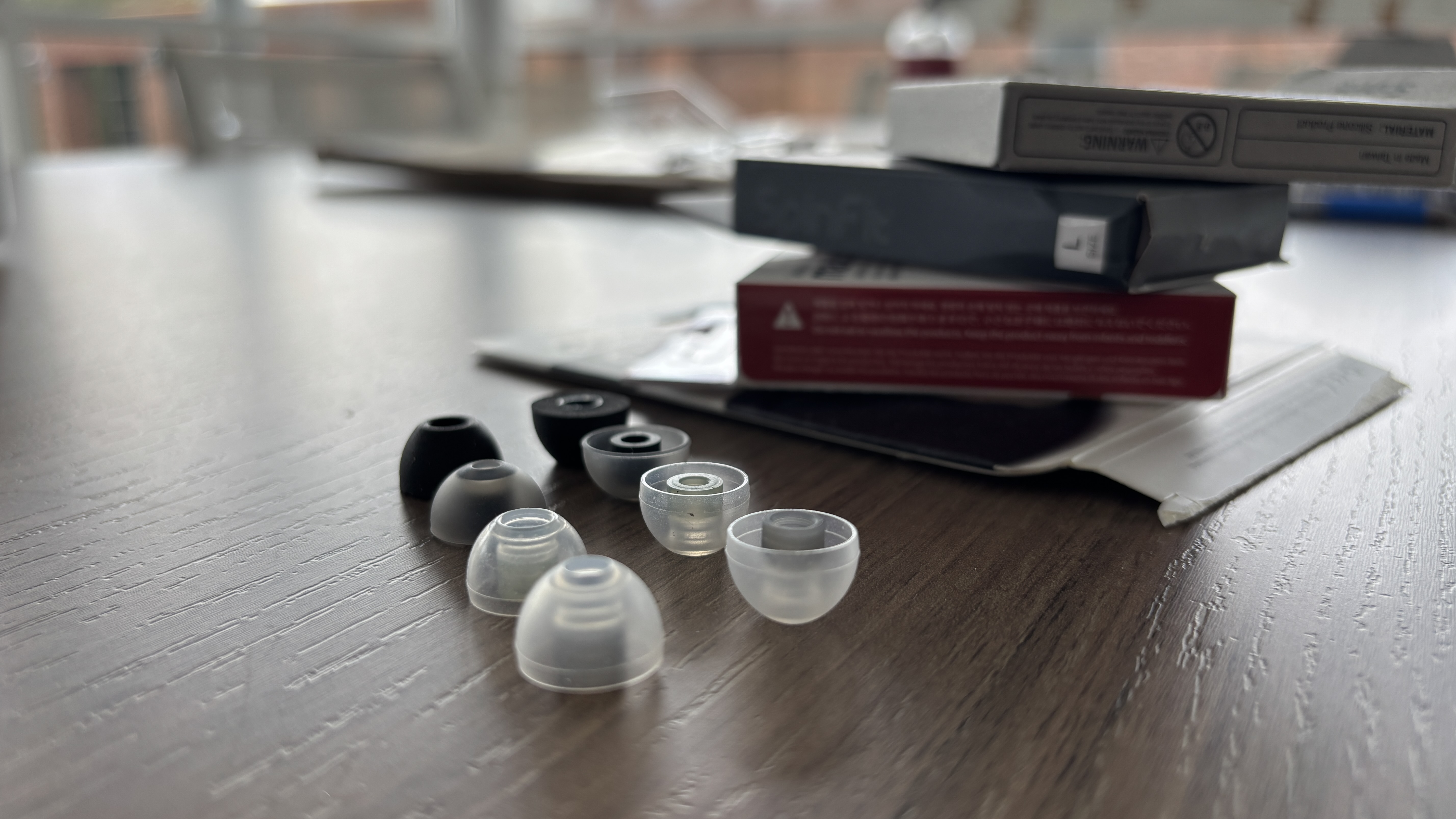 A selection of wireless earbud eartips lined up on a table next to a stack of boxes