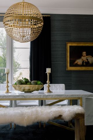 black dining room with marble and gold dining table, sheepskin throw, gold pendant light