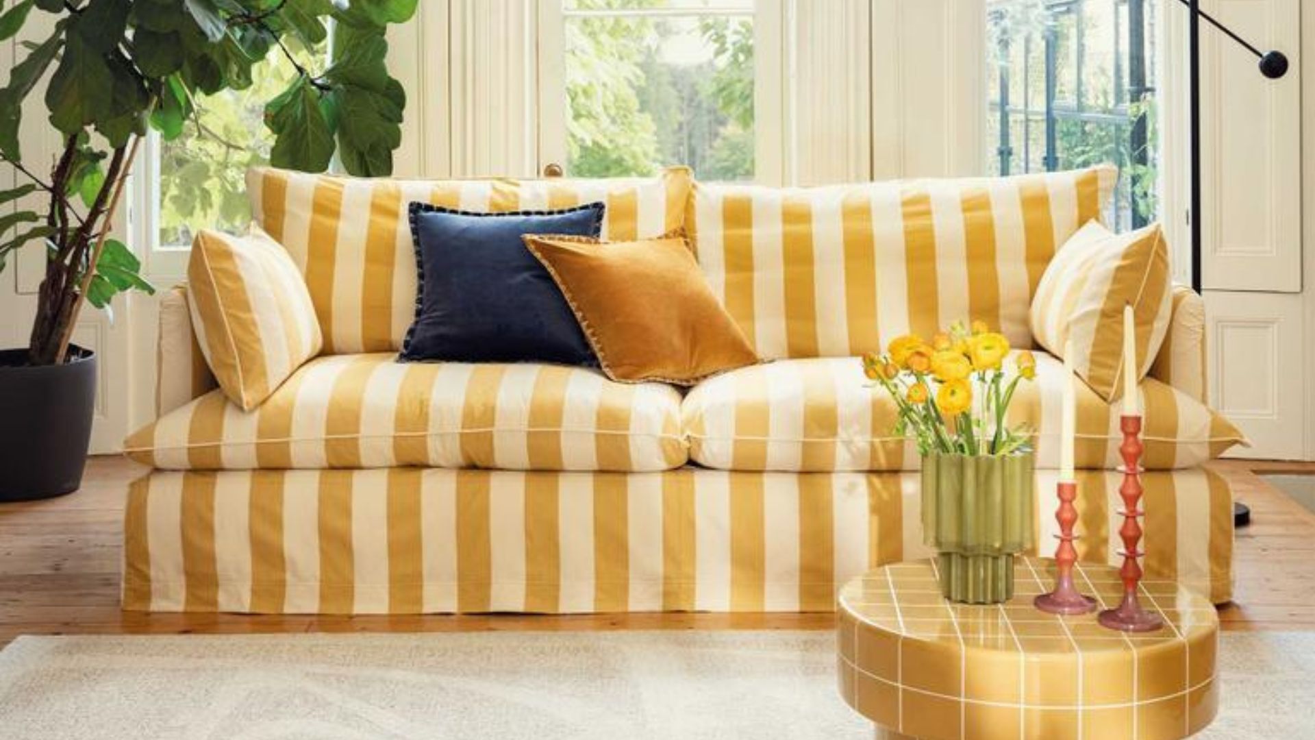 yellow striped sofa with cushions on it
