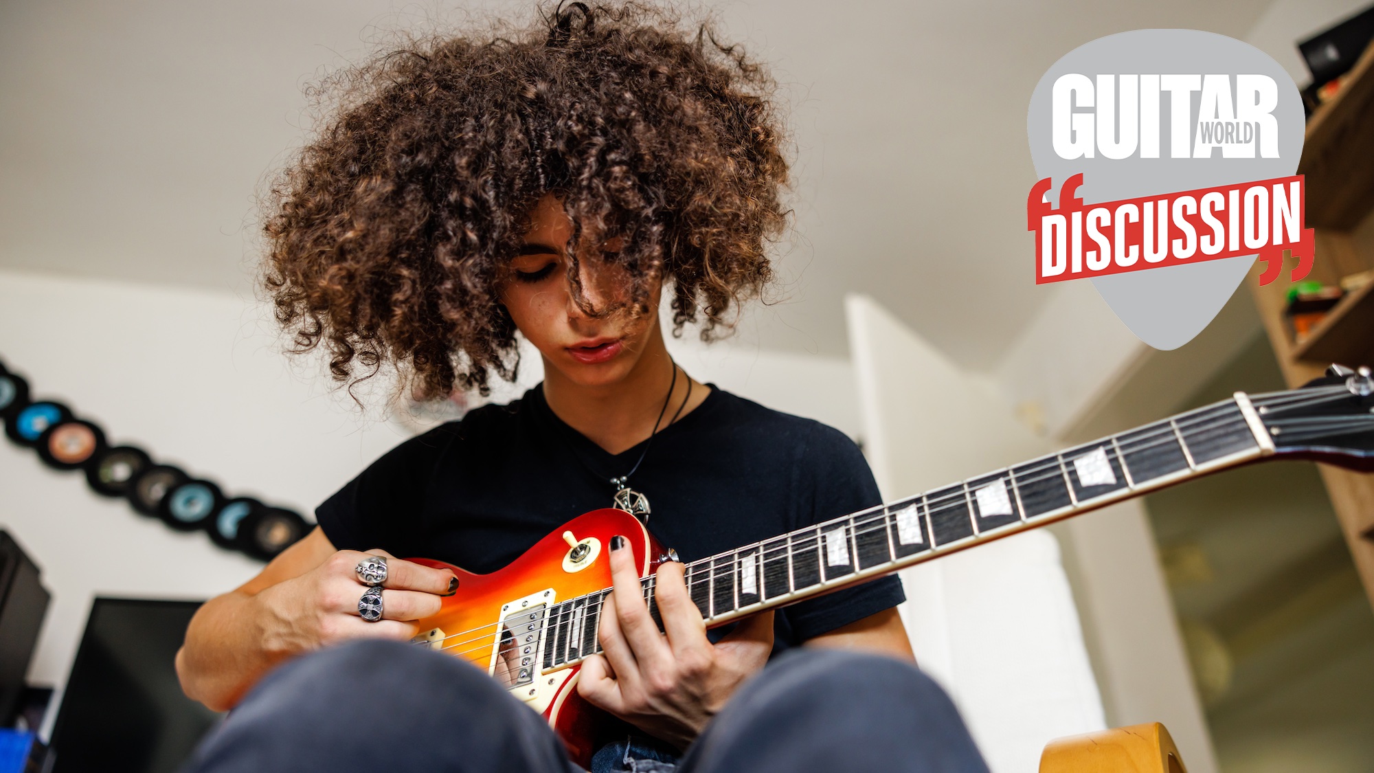 A seated teenager plays a Les Paul 