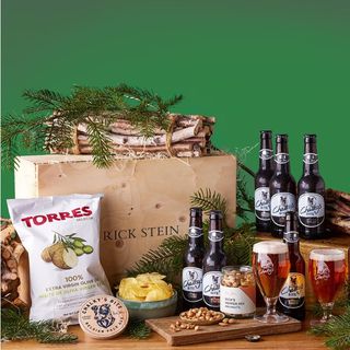 6 bottles of beer, 2 Chalky's Half Pint Glasses, a Chalky's Bottle Opener, Rick Stein Pepper Mix Nuts, Torres Selecta Extra Virgin Olive Oil Potato Chips pictured on a green background 
