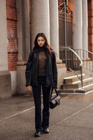 woman wearing sheer top, leather jacket, jeans, and boots