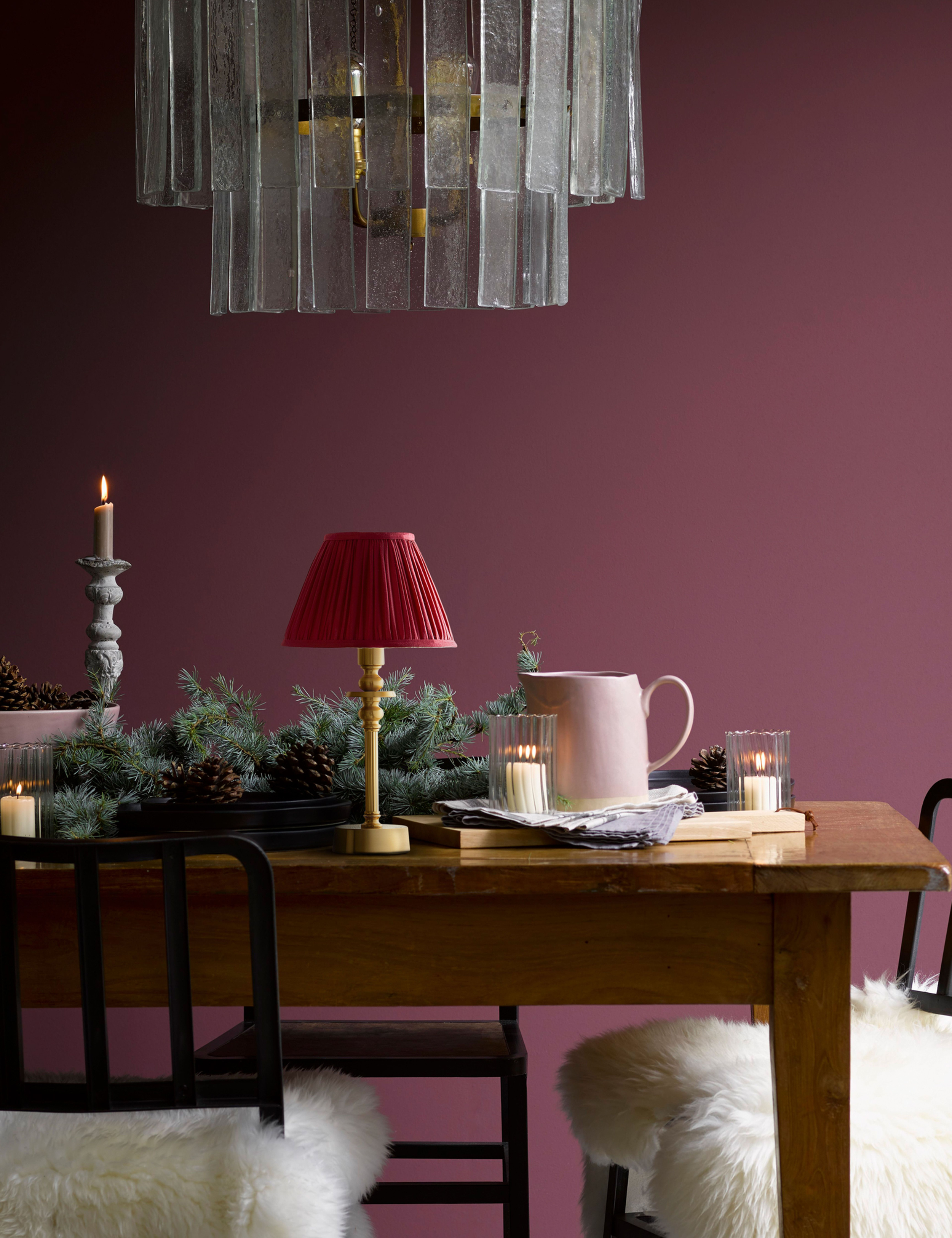 Red pleated velvet shade portable table lamp set on a wooden dining table styled with holiday decor