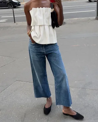 @sylviemus_ wearing a House of Dagmar strapless top, wide-leg jeans, and ballet-flat mules