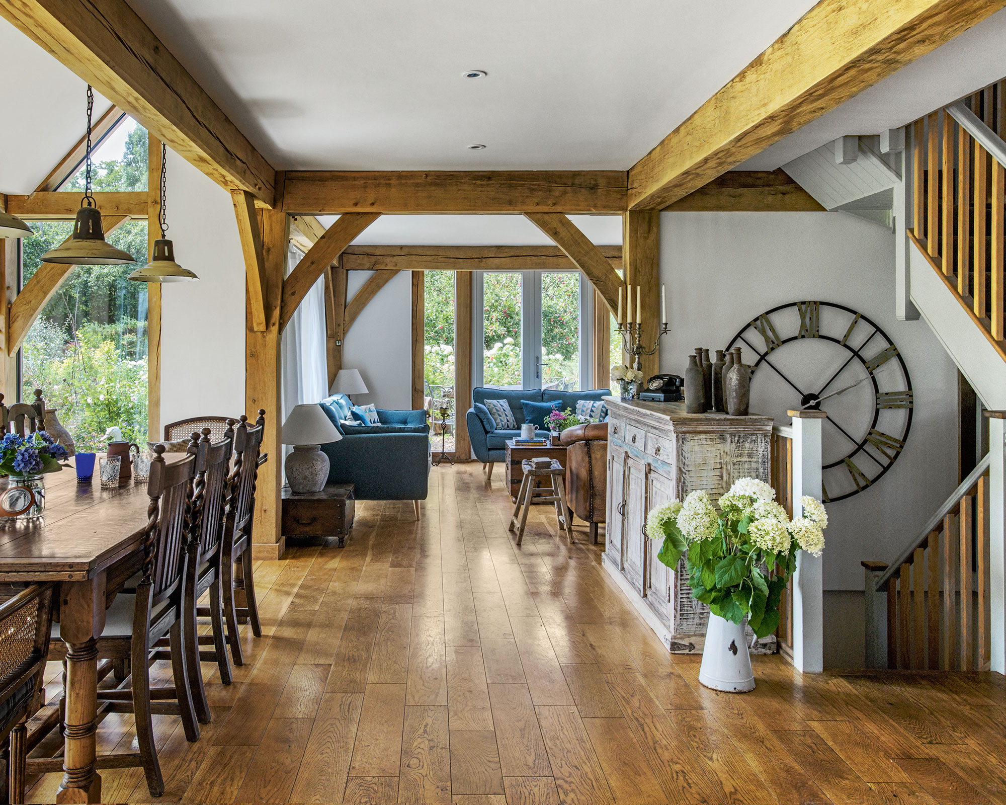 Open plan living room with wooden floors, white walls and beams