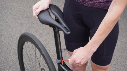 Female cyclist adjusting her bike saddle height