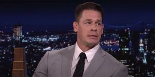 John Cena in a grey suit with a white shirt and black tie sitting for an interview on The Tonight Show.