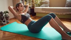 Woman holding midway of sit-up position at home