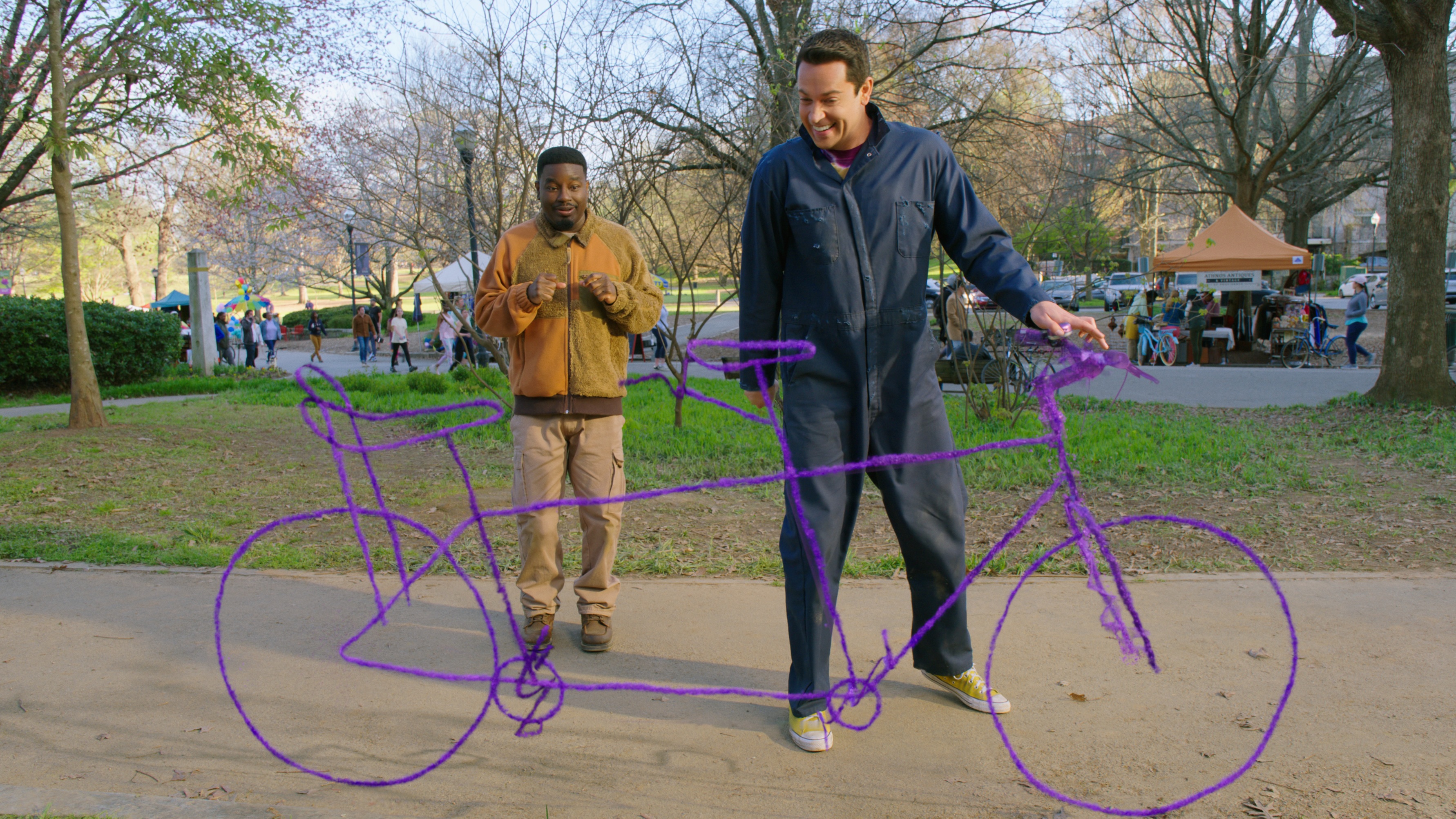 Moose (Lil Rey Howery) and Harold (Zachary Levi) stand next to a tandem bicycle drawn in purple crayons on 